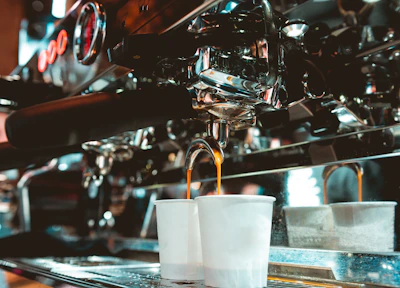 Close-up of hands skillfully preparing espresso with a professional machine in a cozy café setting.