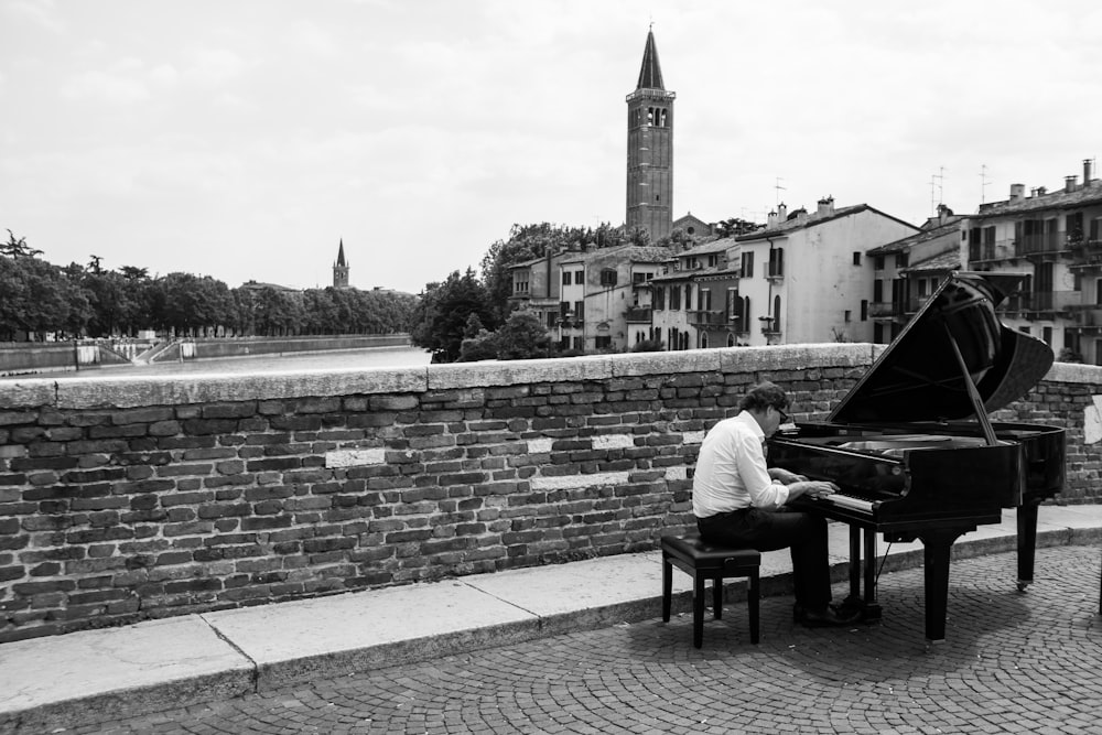 grayscale photo og man playing upright piano