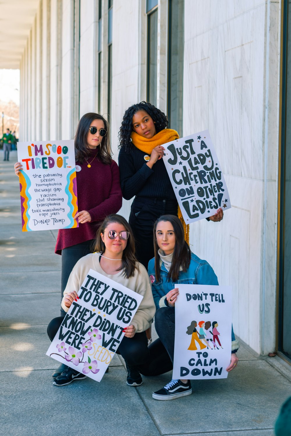 four woman holding signages near wall