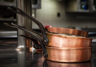 three brass colored cooking pans