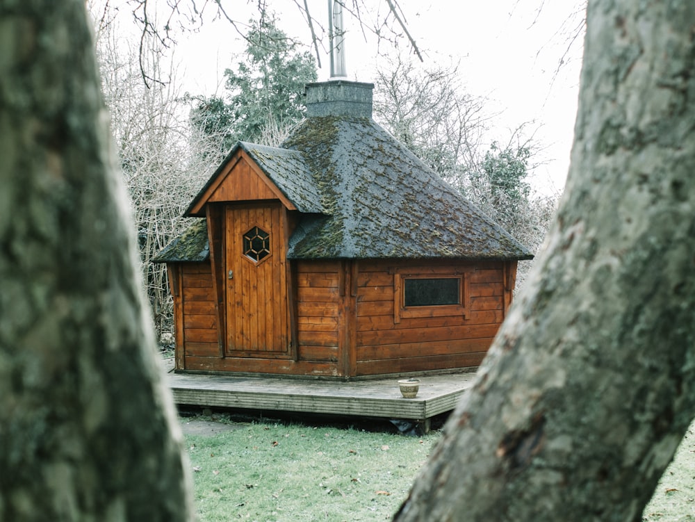 Braunes Holzhaus in der Nähe von Bäumen während des Tages