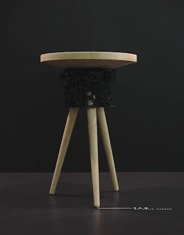 A finished wooden stool displayed proudly by a happy workshop participant.