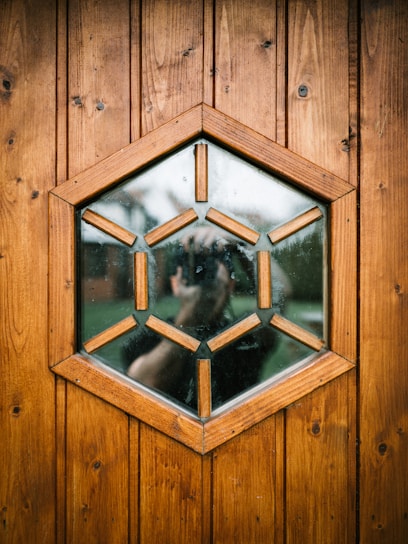 A warm honey-gold hexagonal cabin doorway framed by soft neutral-toned natural wood.