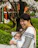 A smiling mother gently holding her baby wrapped in a soft, colorful baby wrap outdoors.