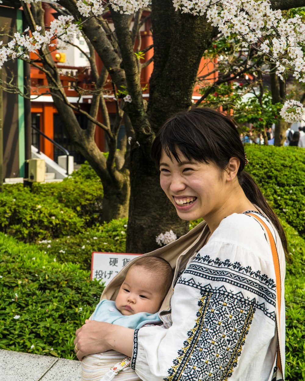 昼間に赤ん坊を運ぶ笑顔の女性