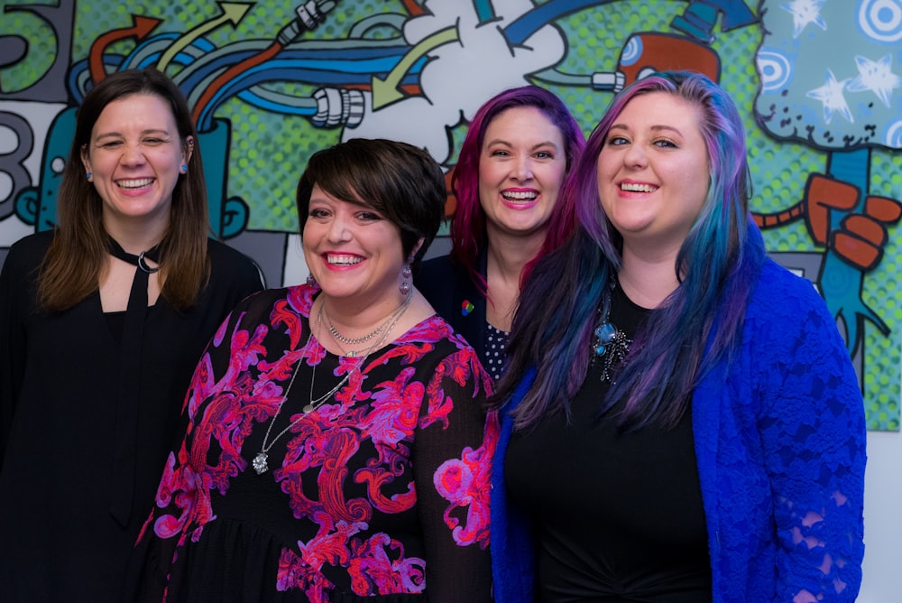 four smiling womens standing inside room