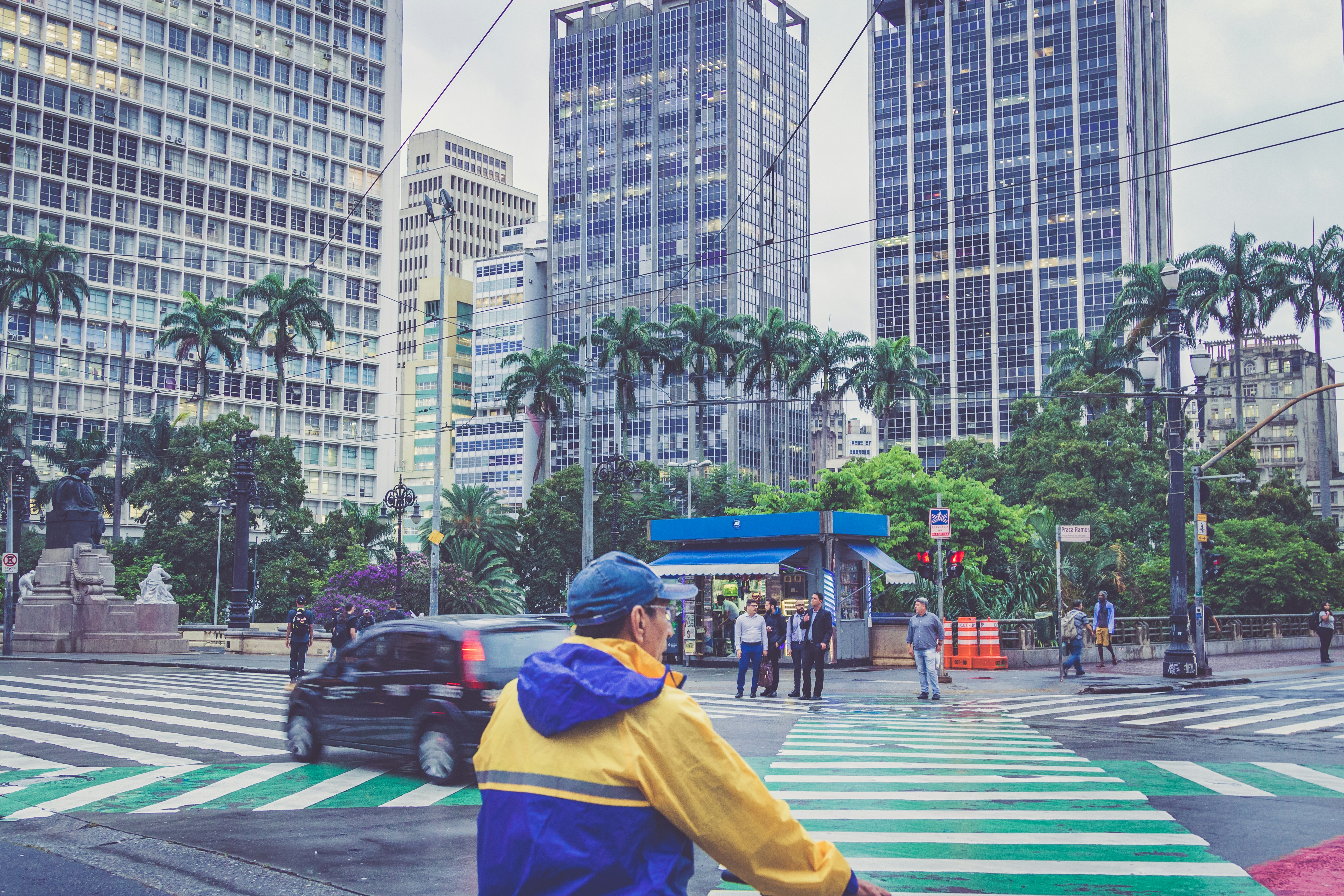 Mann trägt tagsüber gelb-blauen Regenmantel in der Nähe der Straße
