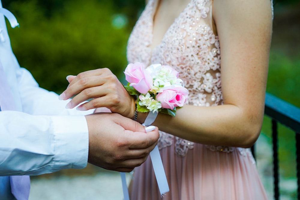 man putting pink and white floral decor to woman's hand