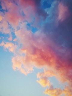 A soft, dreamy cloudscape blending into a vibrant city skyline at dawn.