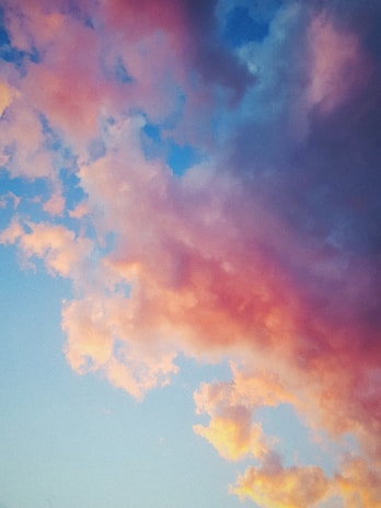 A soft, dreamy cloudscape blending into a vibrant city skyline at dawn.