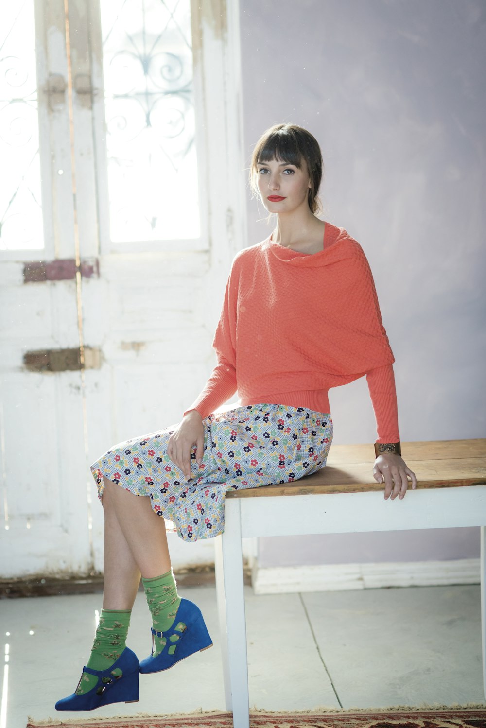 woman orange shirt and floral skirt sitting on table
