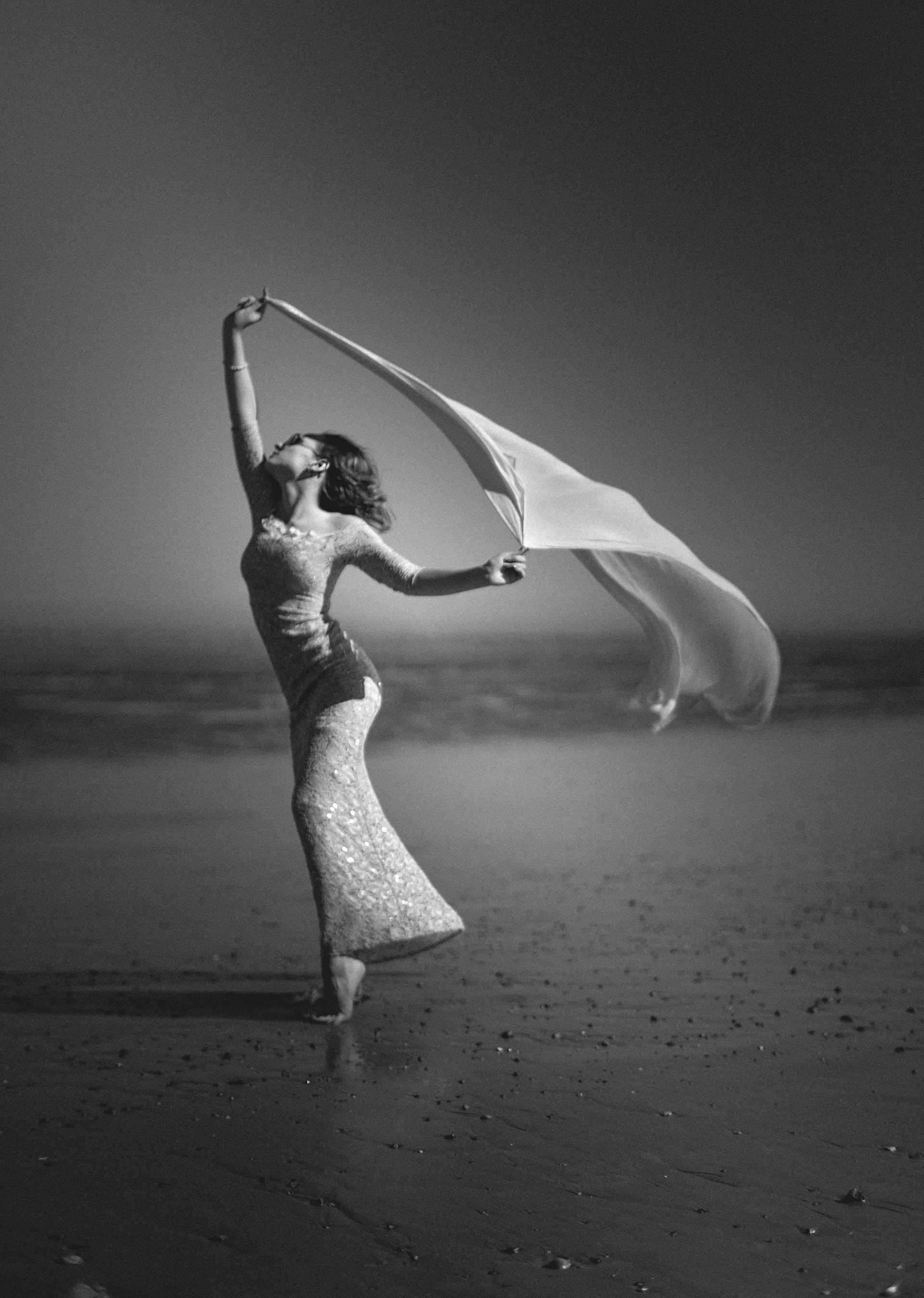 A dynamic shot of women in elegant black and white fitness wear moving gracefully along a sunlit beach, with golden sunlight highlighting the fabric details.
