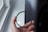 A hand is holding a circular camera filter near a window. The filter is labeled with markings that include 'B+W' and 'UV-Haze'. The background shows an out-of-focus window and wall, creating a soft lighting effect.