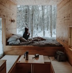 woman sitting on bed watching by the window during winter