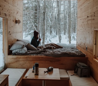 woman sitting on bed watching by the window during winter