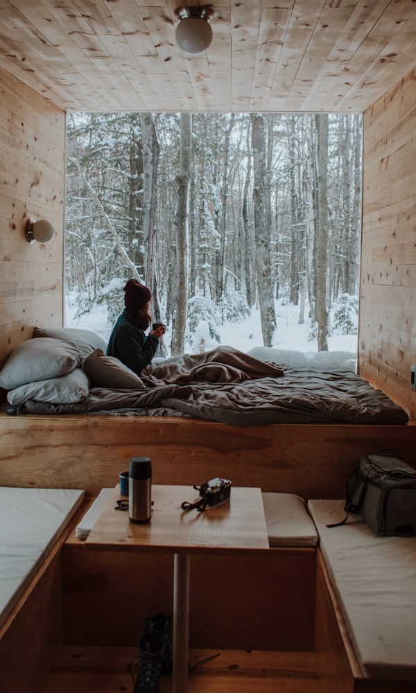 woman sitting on bed watching by the window during winter by Nachelle Nocom (https://unsplash.com/@nachellenocom)