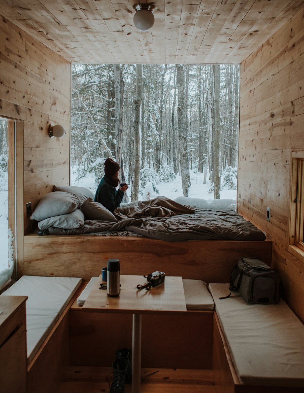 Donna seduta sul letto che guarda dalla finestra durante l'inverno