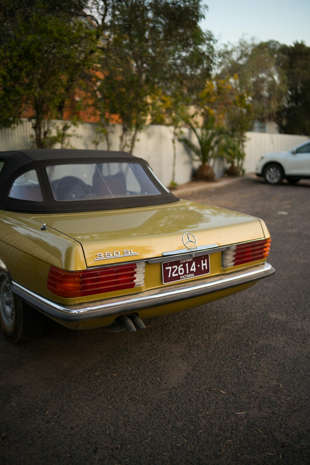 brown Mercedes-Benz vehicle parked near wall and trees