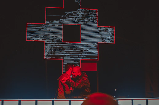 Two people warmly shaking hands in front of a softly glowing cross symbol.