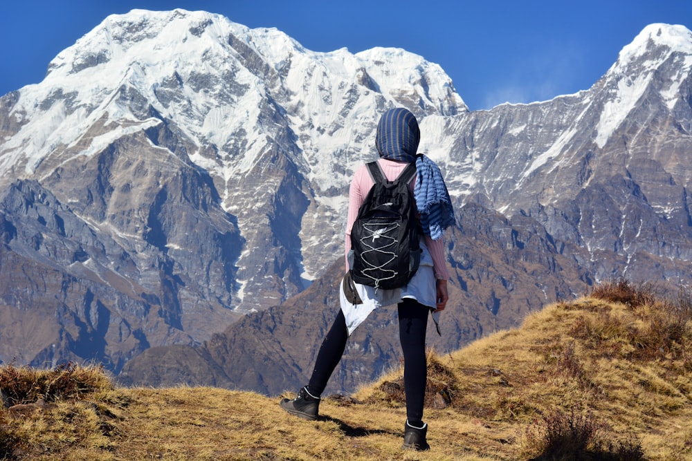 Persona que lleva una mochila negra a través de la montaña blanca