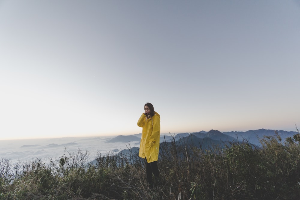 woman in yellow coat on top of hill