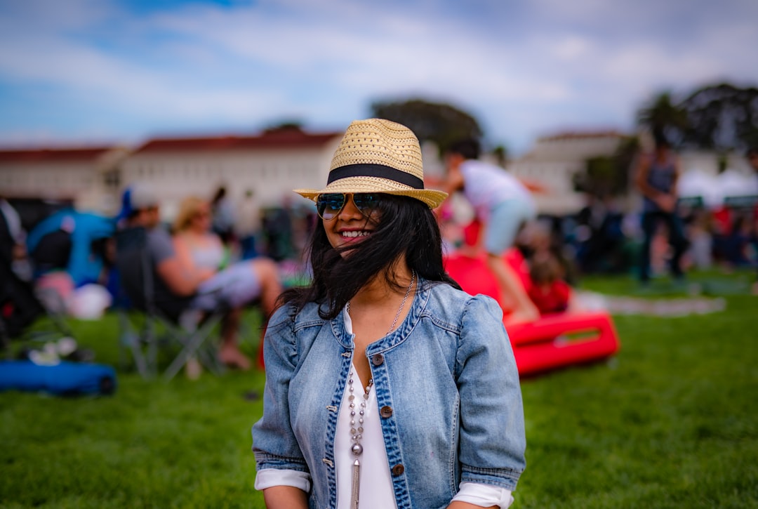 smiling woman while standing on green grass field near peoplle