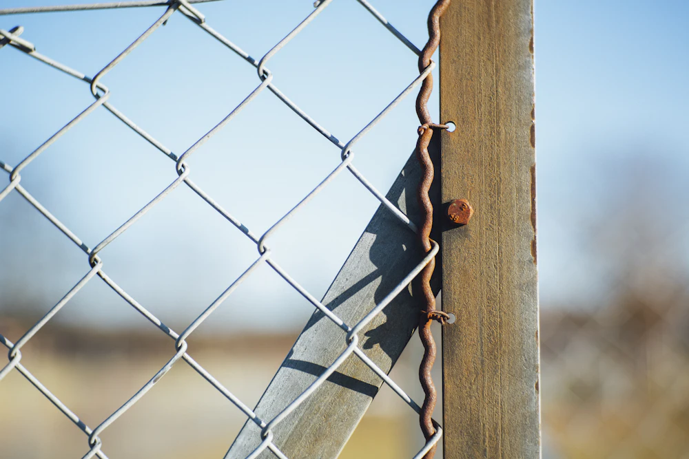 Close view of a chain link fence and post against blue sky