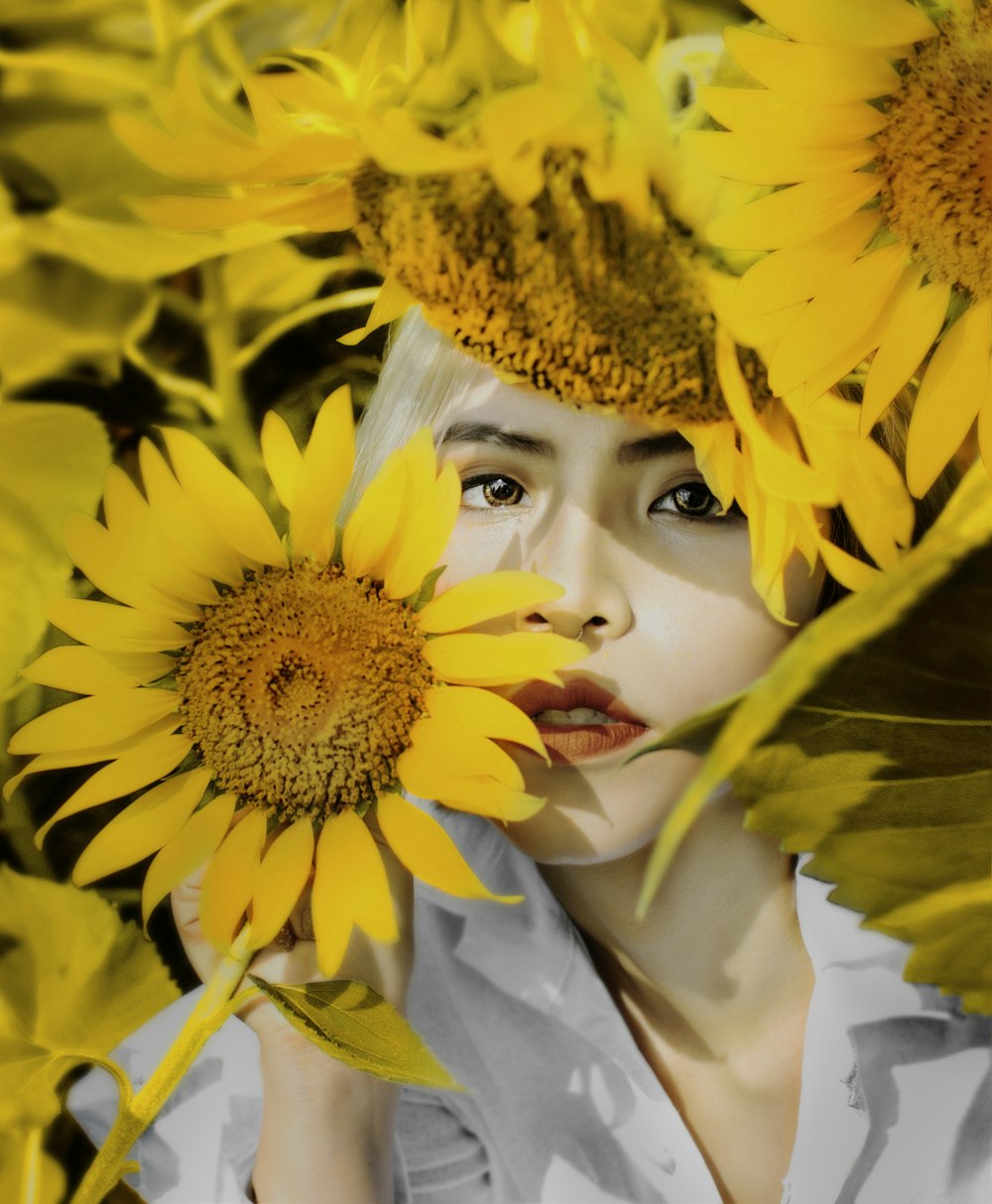 woman under shade and holding sunflower in selective focus photography