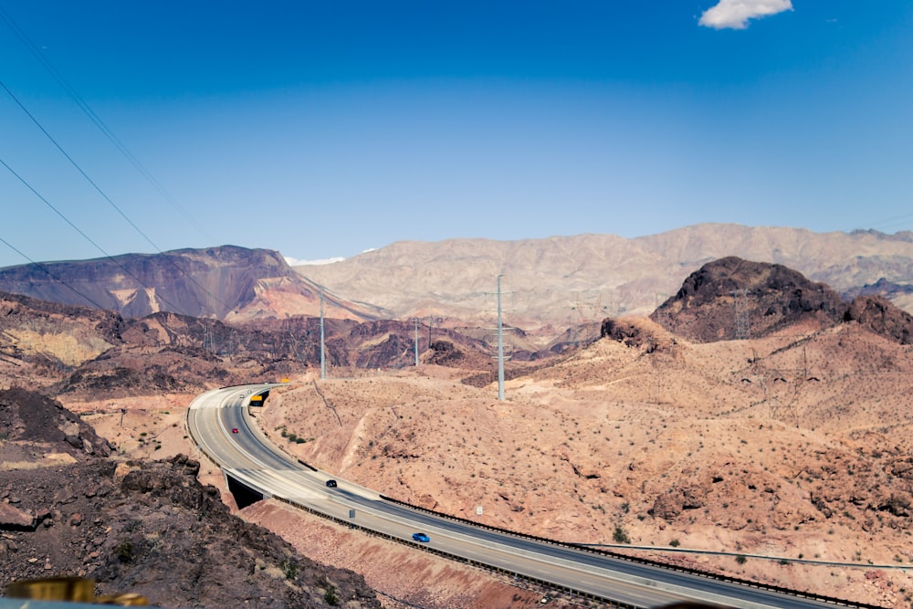 cars passing on highway overlooking hills and sand dunes at daytime