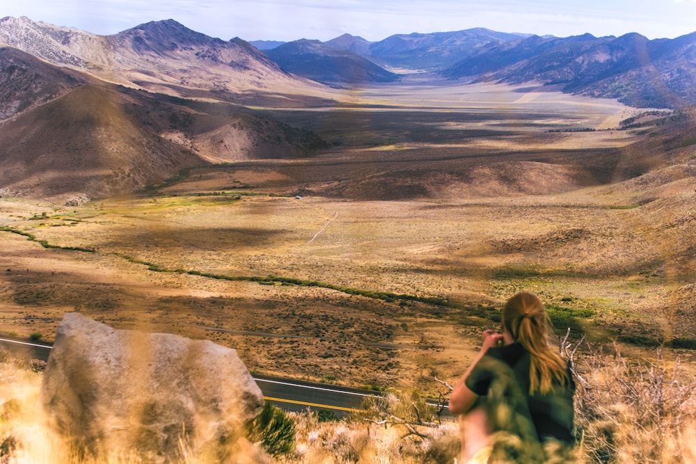 woman sitting near mountains