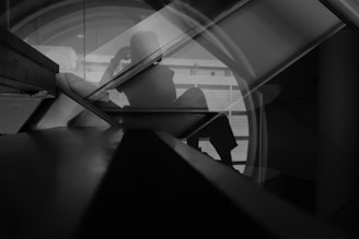 A silhouette of a person sitting against a geometric background, with lines and reflections creating an abstract, introspective scene.