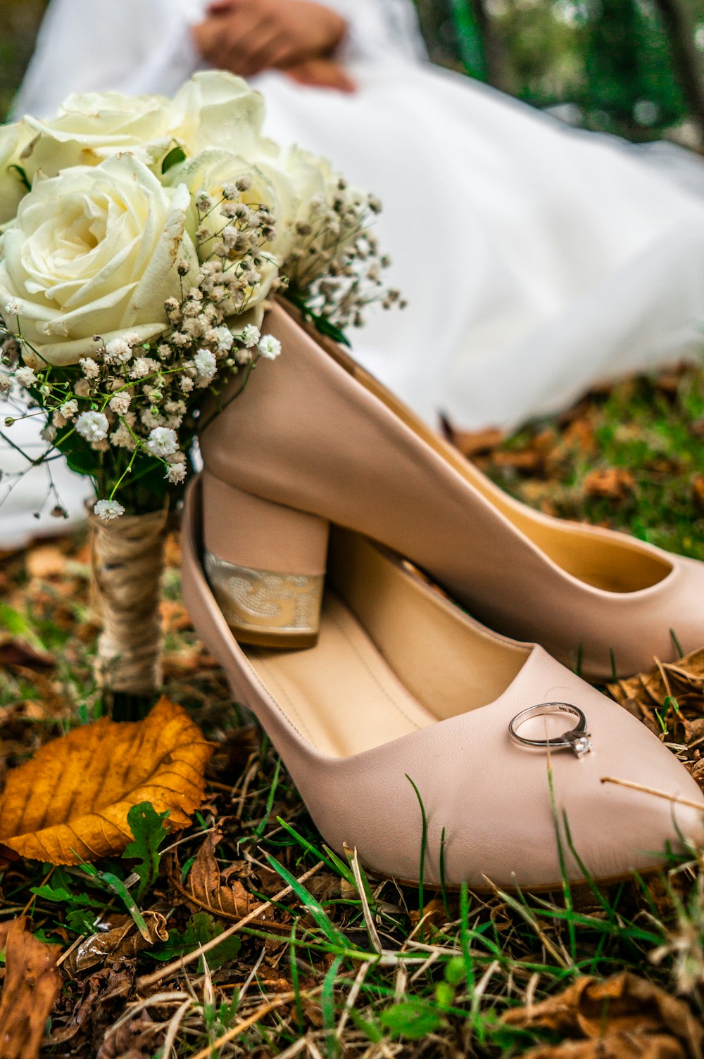 gold solitaire ring placed on top brown leather shoe on grass