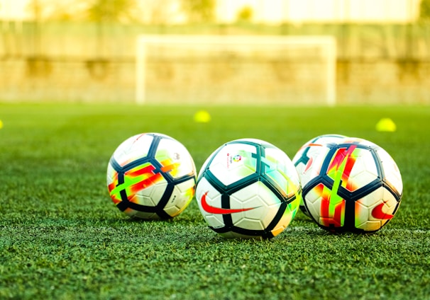 three white-and-black soccer balls on field