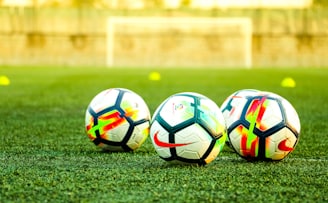 three white-and-black soccer balls on field