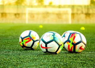 three white-and-black soccer balls on field