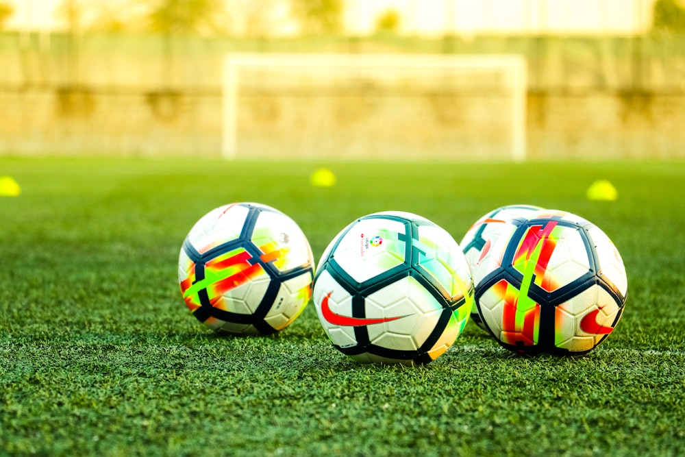 three white-and-black soccer balls on field