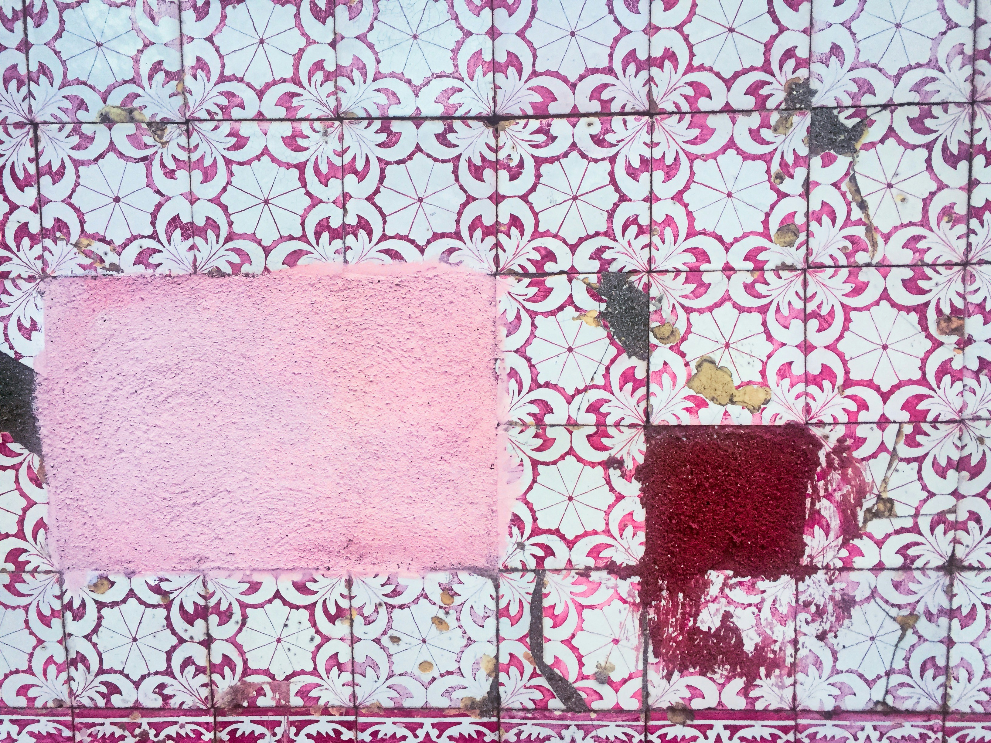 a piece of pink and red paint on a tile wall