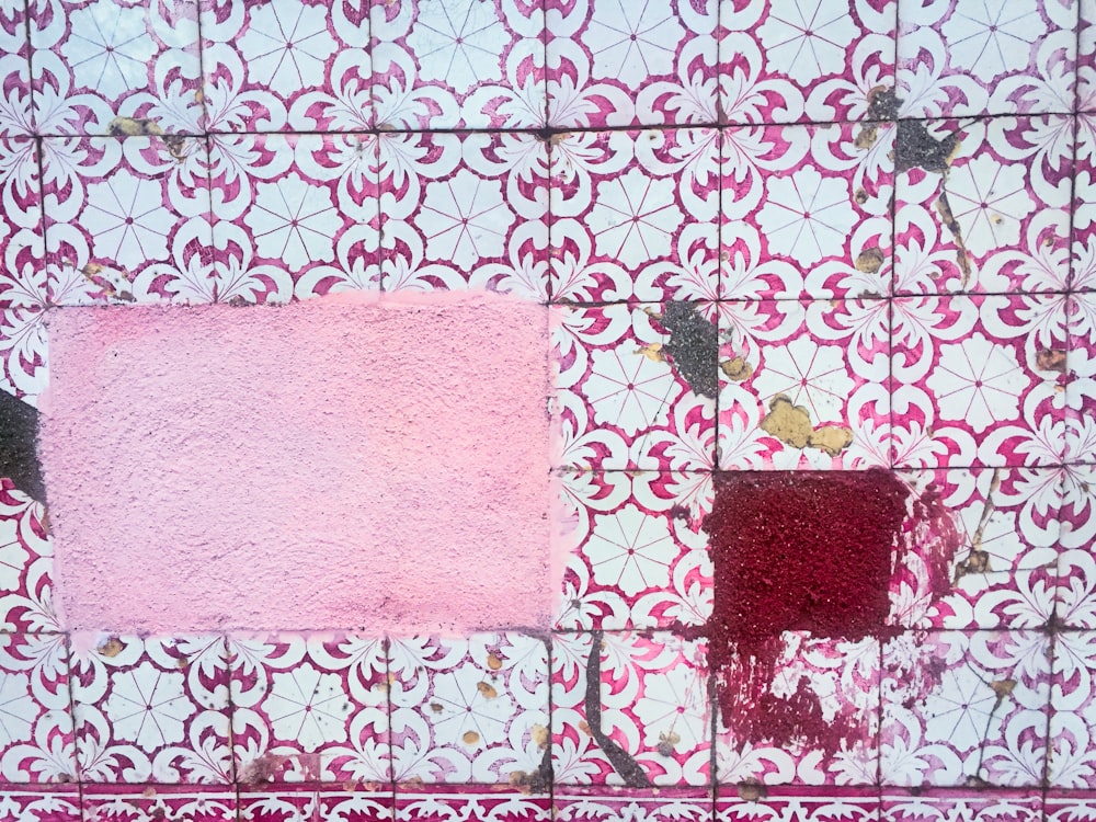 a piece of pink and red paint on a tile wall