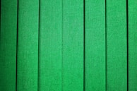 Vertical green panels with a fabric-like texture, evenly spaced and aligned, creating a repetitive pattern.