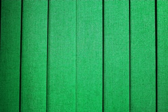 Vertical green panels with a fabric-like texture, evenly spaced and aligned, creating a repetitive pattern.