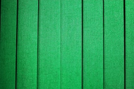 Vertical green panels with a fabric-like texture, evenly spaced and aligned, creating a repetitive pattern.