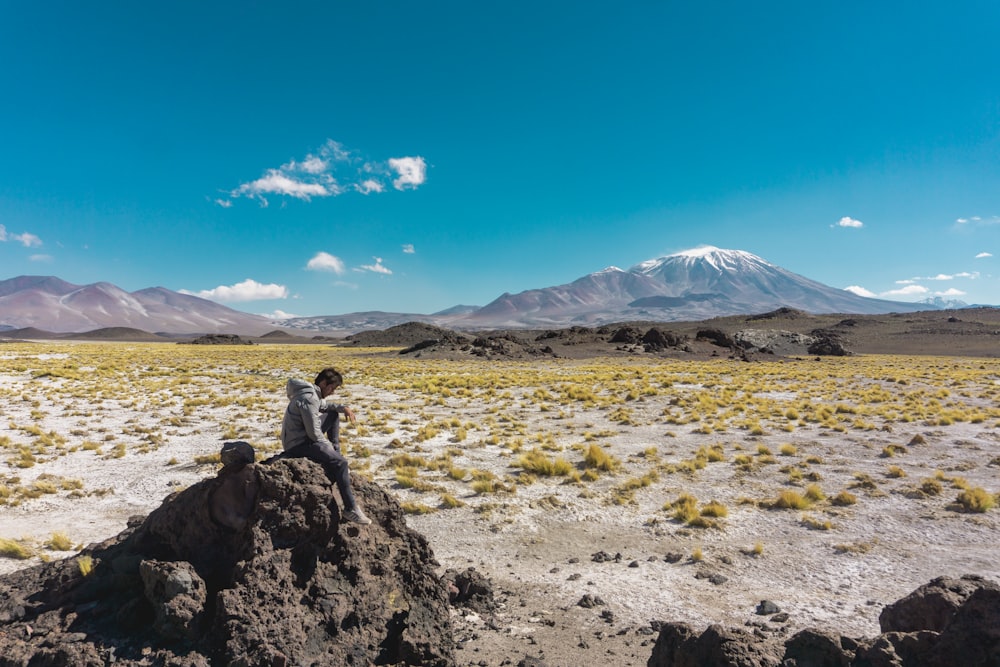 a person sitting on a rock in the middle of a desert