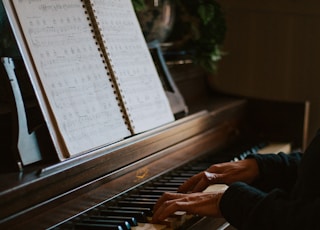 man playing the piano in front of open music book