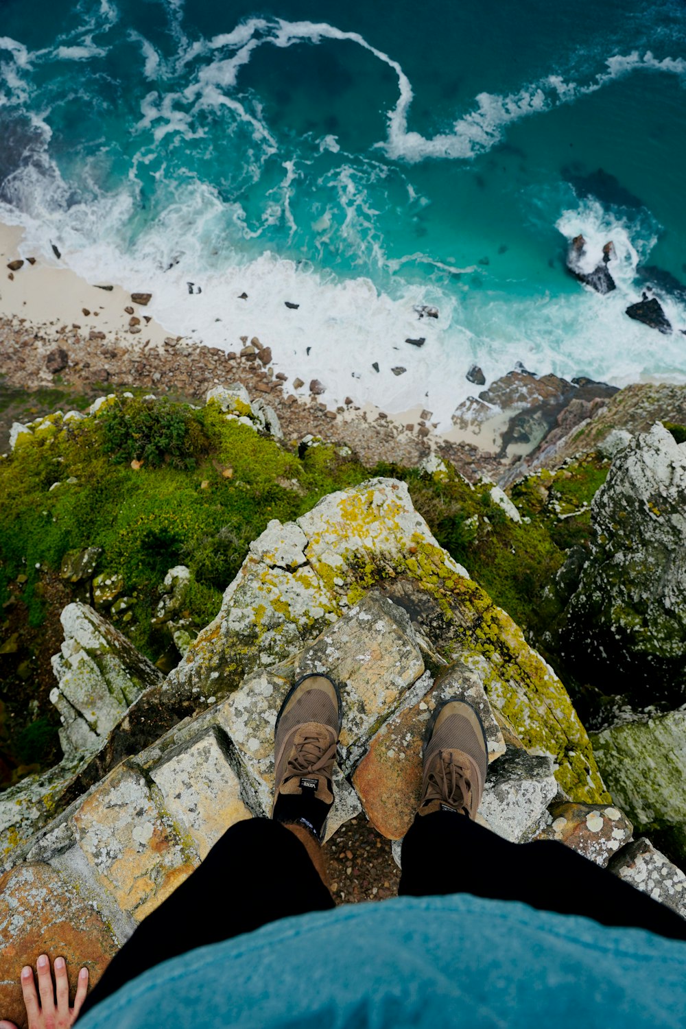 person in black pants standing on cliff