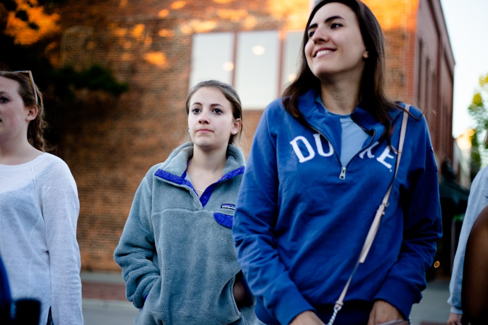 three woman standing near brown concrete building