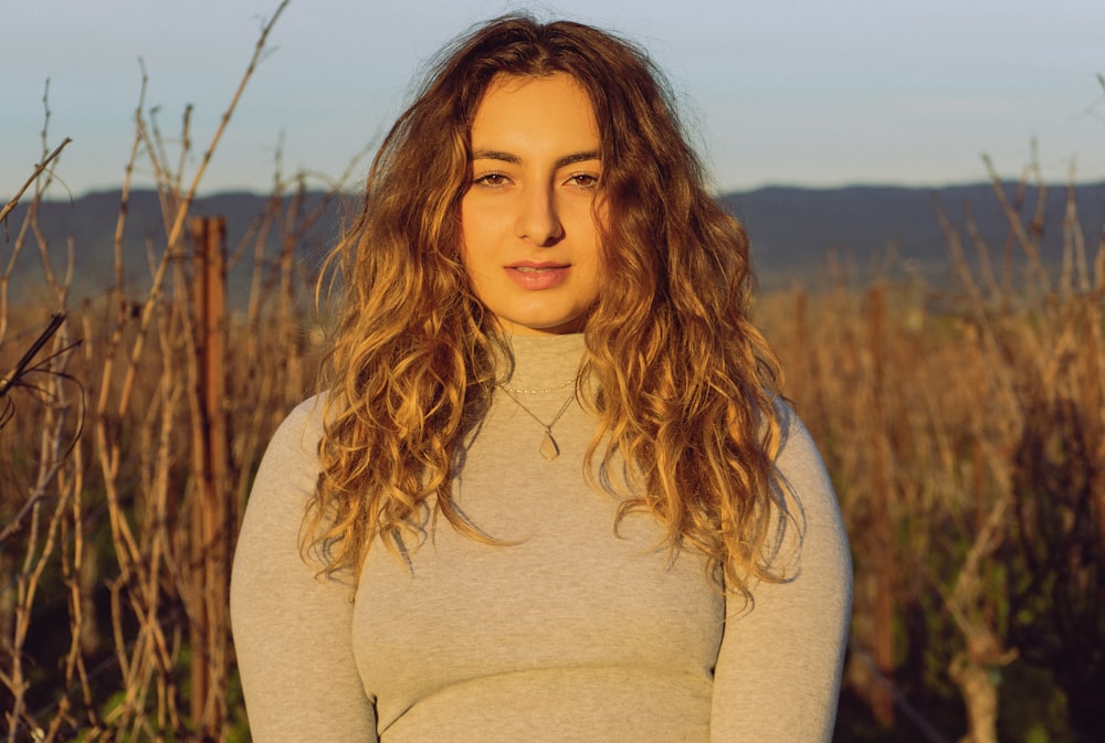 woman wearing grey crew-neck long sleeved shirt surrounded by brown field