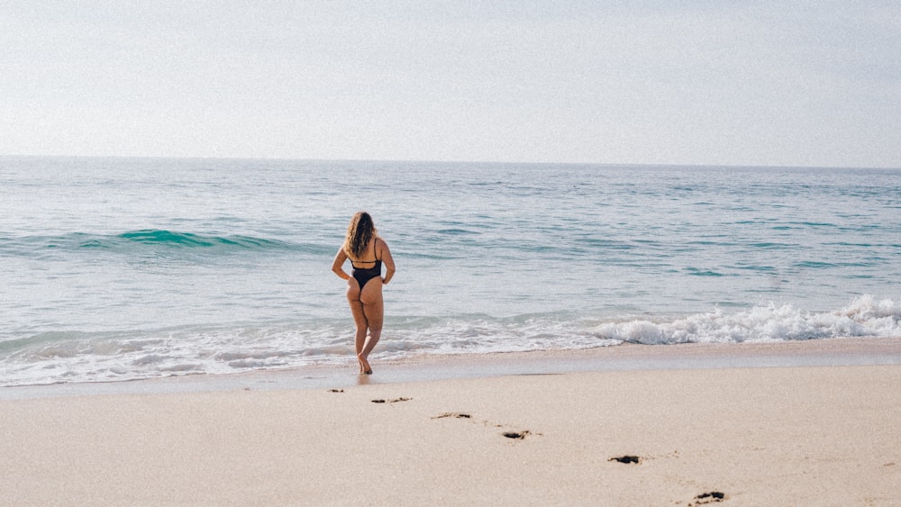 woman walking on shore at daytime