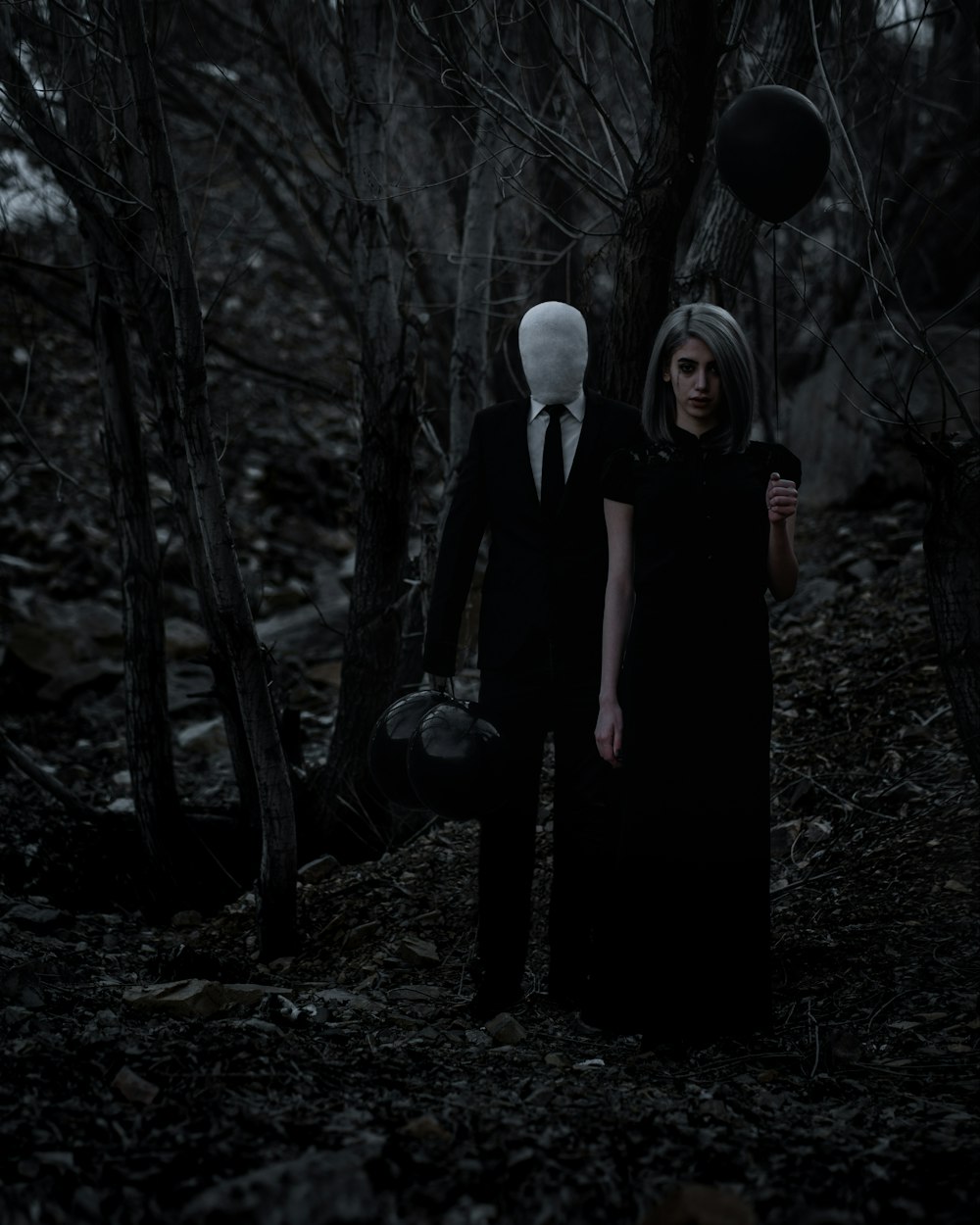 man and woman standing in the middle of forest