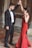 A couple engaged in a dance, with the man wearing a formal black suit and bow tie and the woman in a long red dress. They are standing on a tiled floor with dry leaves scattered around, possibly in an outdoor or historical setting with stone walls.