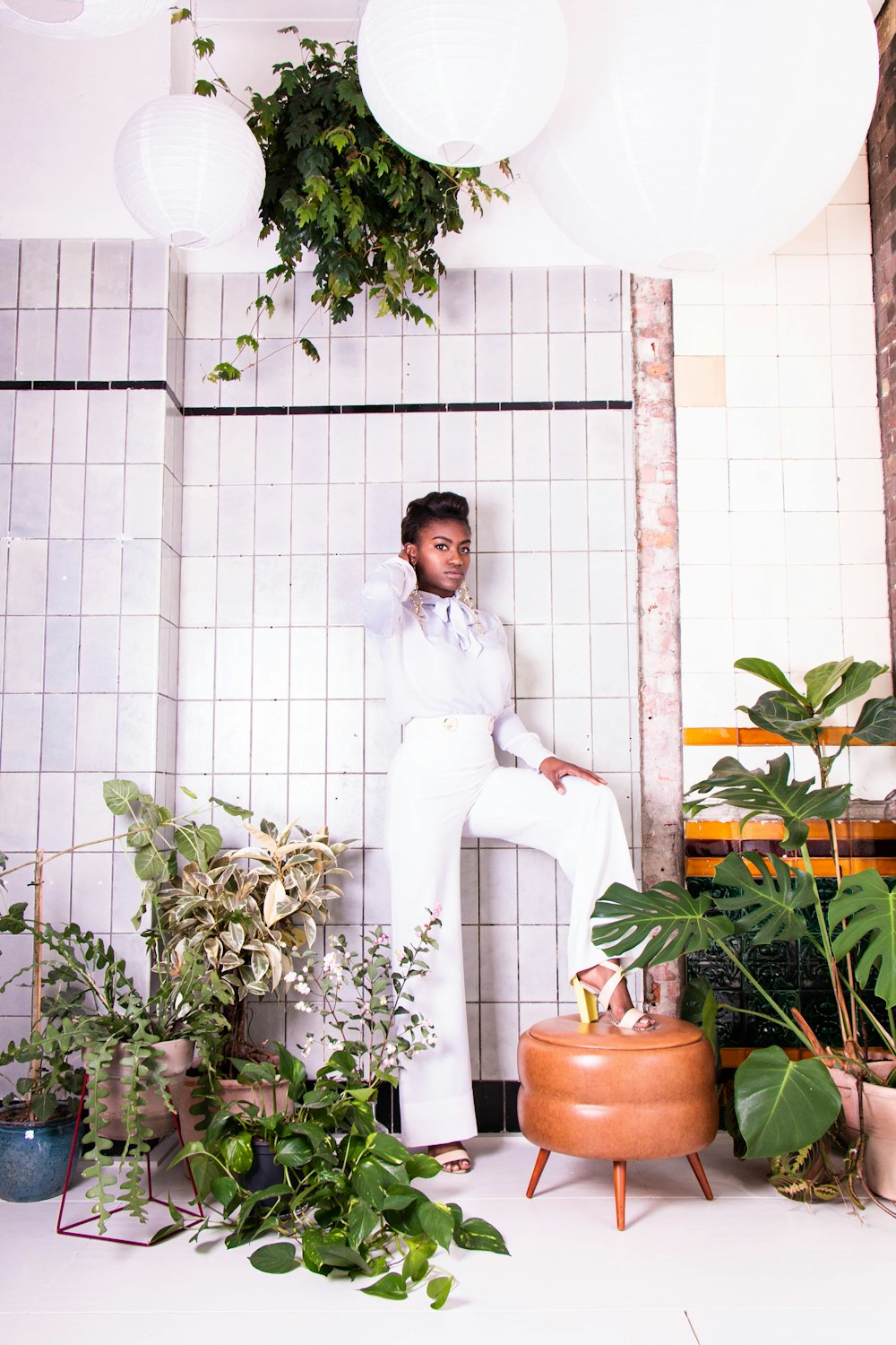 a man sitting on a stool surrounded by plants